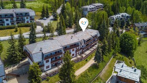 An aerial view of a multi-story building with balconies, surrounded by trees and other buildings. - Appartamento la Cerbiatta 5min Jouvenceaux Lift (Sauze d'Oulx)
