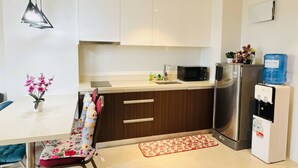 Una cocina moderna con gabinetes blancos, un refrigerador de acero inoxidable, un microondas y un dispensador de agua.