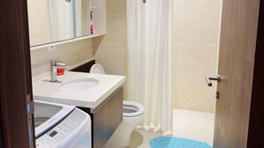 Un baño moderno con un espejo grande, un lavamanos, un inodoro y una zona de ducha.