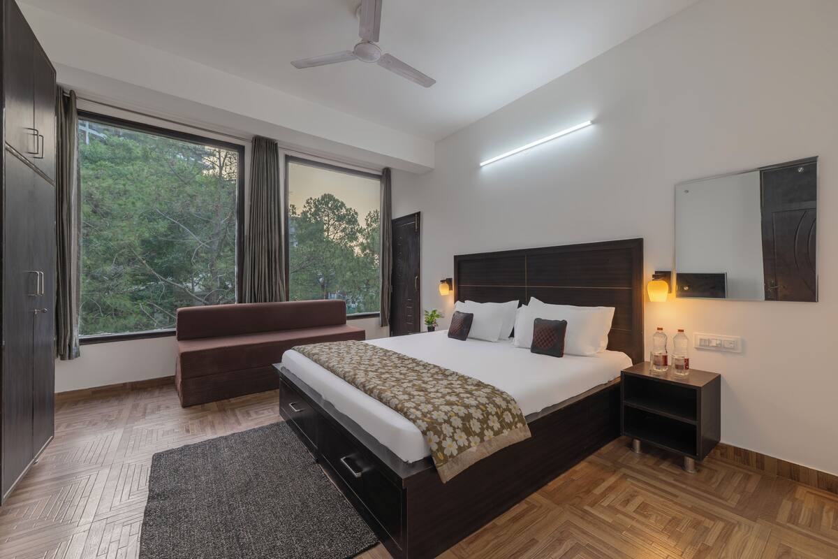 Un dormitorio moderno con una cama grande, un banco, una mesita de noche y un ventilador de techo.
