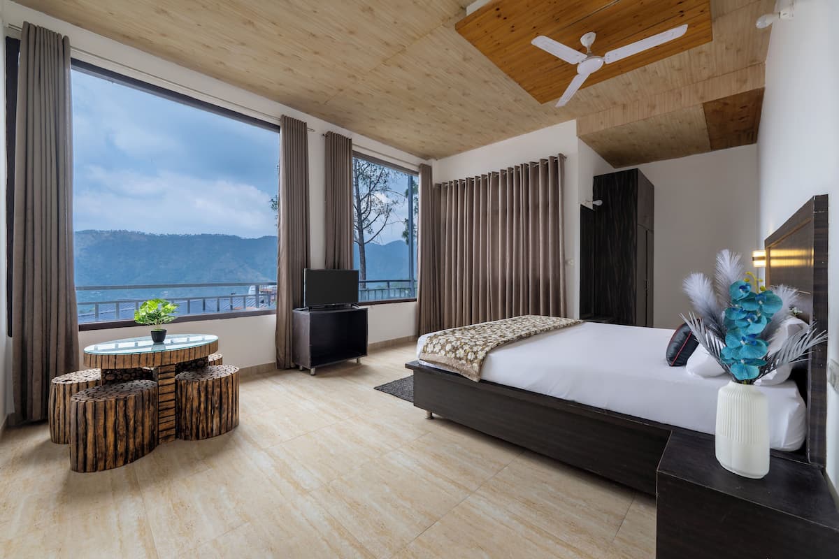Un dormitorio moderno con una cama grande, televisión, techo de madera y vistas a la montaña.