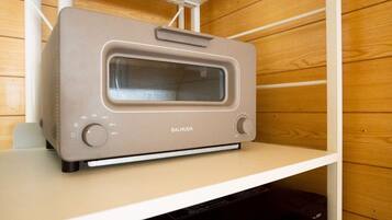 A beige toaster oven on a white shelf in a wooden-paneled kitchen.