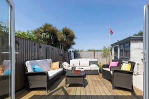 An outdoor patio with wicker furniture, a hot tub, and a flag.