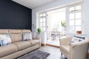 Ein Wohnzimmer mit einem beigen Sofa, einem passenden Sessel und einem grauen Teppich.