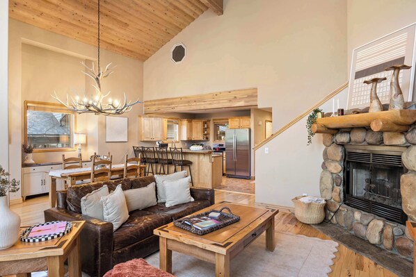 A spacious living room with a fireplace, a dining area, and a kitchen.