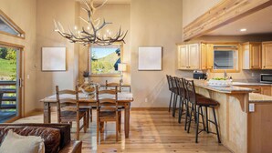 A spacious kitchen with wooden cabinets, a dining area with a large table and chairs, and a unique antler chandelier. - 3BR Near Slopes & Main | Hot Tub + Modern Comfort (Park City)