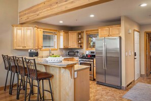 A kitchen with wooden cabinets, a stainless steel refrigerator, a microwave, and a stove.
