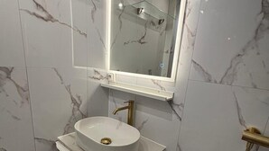 A modern bathroom with a white marble vanity, a large mirror, and a gold faucet. - Studio Croisette 3 mint on foot, comfortable and relaxing. (Cannes)