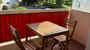 A balcony with a red awning, two wooden chairs, and a table. - Studio Croisette 3 mint on foot, comfortable and relaxing. (Cannes)