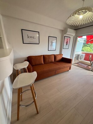 A modern living room with a brown sofa, two white chairs, and a unique ceiling light fixture.