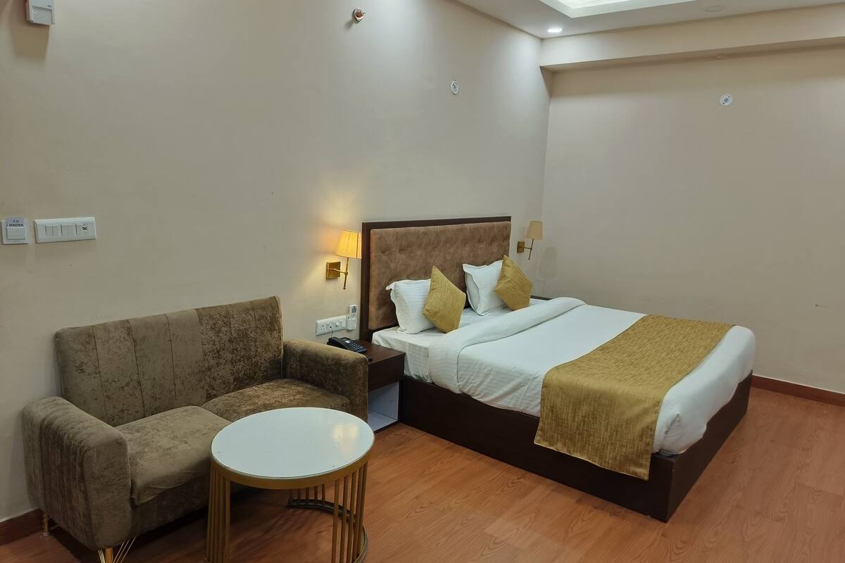 Une chambre d’hôtel comprenant un lit, un canapé, une petite table et une table de chevet avec une lampe.