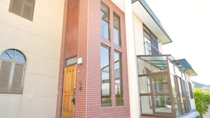 Un bâtiment moderne avec une façade en briques, de grandes fenêtres et une porte en bois.
