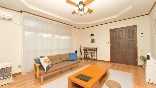 Un salon avec un canapé en bois, une table basse et un ventilateur de plafond.