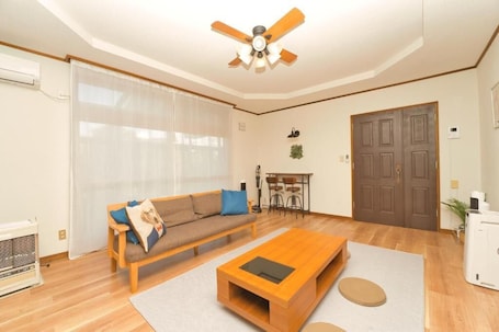 A living room with a wooden sofa, a coffee table, and a ceiling fan.