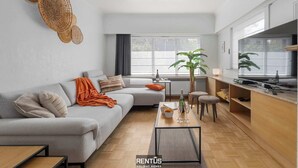 A modern living room with a sofa, coffee table, and a dining area with a bar. - Coppietershof-home with garden in historic Bruges (Bruges)