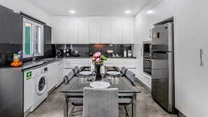 A modern kitchen with a central island, built-in appliances, and a dining area with a glass table.