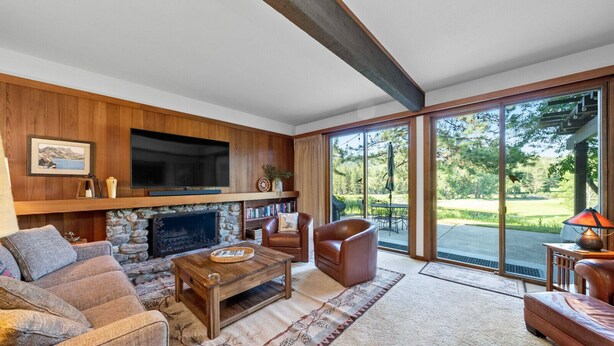 A spacious living room with a stone fireplace, leather sofas, a coffee table, and a large TV mounted on the wall. - 3BR on Graeagle Meadows Golf Course (Graeagle)