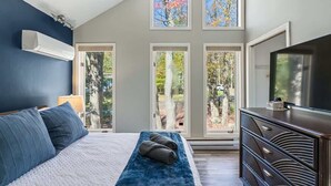 Ein Schlafzimmer mit einem Bett, einem Schminktisch und großen Fenstern.