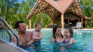 A swimming pool with a wooden deck and lounge chairs in the background. - The Hideaway Club | Heated Pool & Game Room (McDonald)