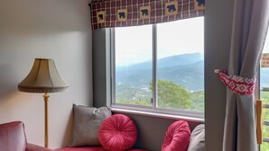 Ein Zimmer mit Fensterbank, Lampe und Bergblick.