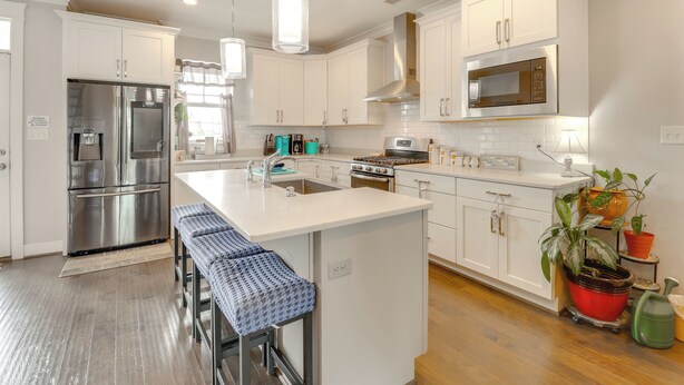 A modern kitchen with white cabinetry, stainless steel appliances, and a central island with bar stools. - Walk to Ocean: Group Getaway in Virginia Beach! (Virginia Beach)