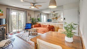 Un salon comprenant un canapé, une table à manger, des chaises, un ventilateur de plafond et des plantes en pot.