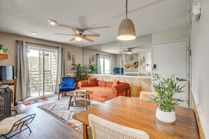 Un salon comprenant un canapé, une table à manger, des chaises, un ventilateur de plafond et des plantes en pot.