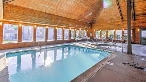 Une piscine intérieure en bois, dotée de grandes baies vitrées et d’une terrasse en béton.
