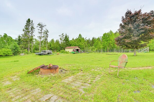 A grassy yard with a wooden chair, a metal chair, and a rusty barrel. - Hike, Fish, Golf & More: Family Getaway in Atlanta (Atlanta)