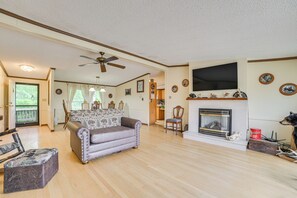 A spacious living room with a fireplace, a sofa, a television, and a ceiling fan. - Hike, Fish, Golf & More: Family Getaway in Atlanta (Atlanta)