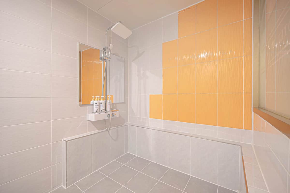 A modern bathroom with a shower, a mirror, and a vanity with toiletries.