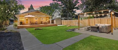 A backyard with a wooden deck, a covered patio area, and a well-maintained lawn.