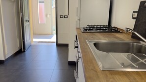 A modern kitchen with a stainless steel sink, wooden countertop, and a gas stove.