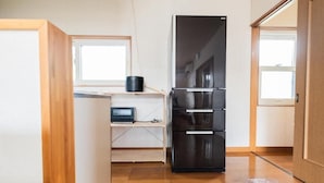 A compact kitchen with a black refrigerator, wooden flooring, and a small window. - UNO Toyako (Toyako)
