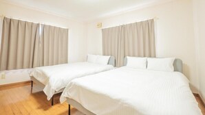 A hotel room with two single beds, beige curtains, and a wooden floor. - UNO Toyako (Toyako)
