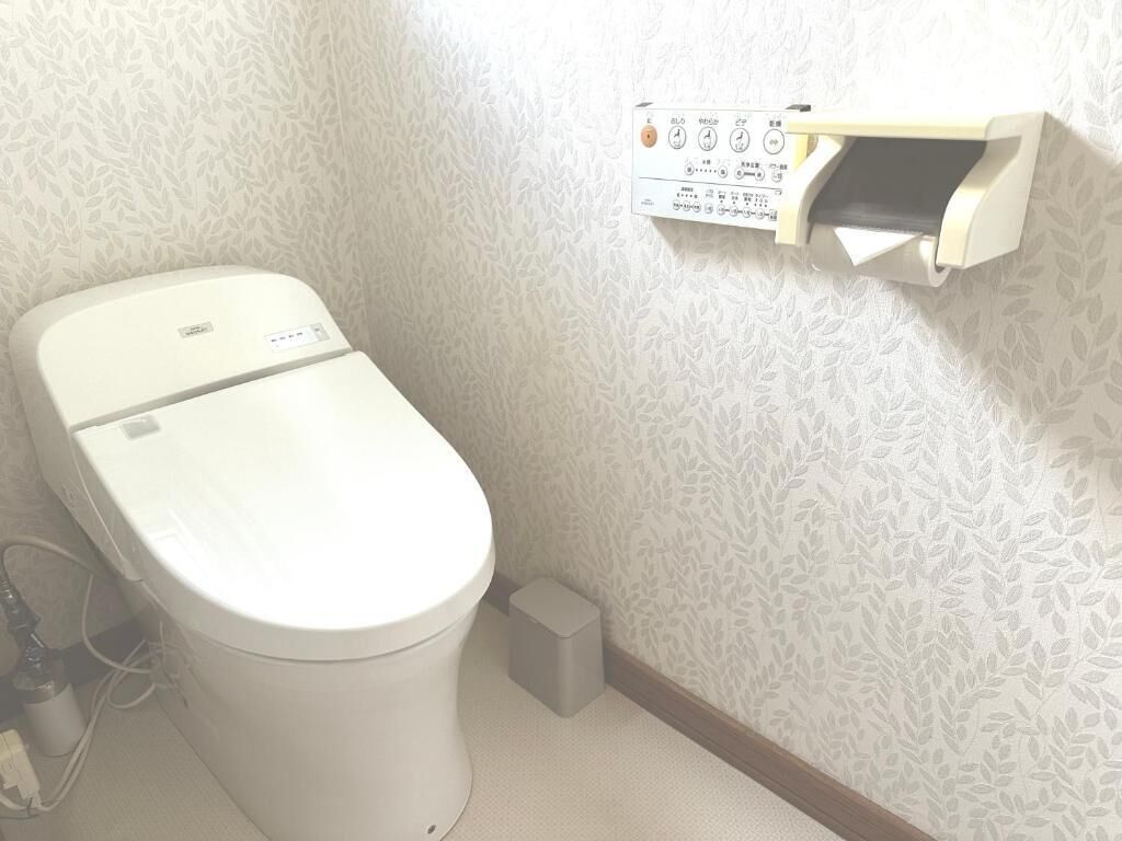 A toilet with a control panel and a small trash bin.