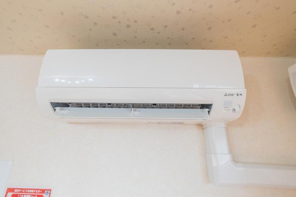 A white air conditioning unit mounted on a wall with a patterned wallpaper background.