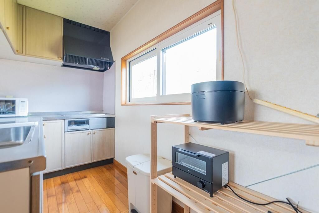 A compact kitchen with a microwave, dishwasher, and a black appliance on a shelf.