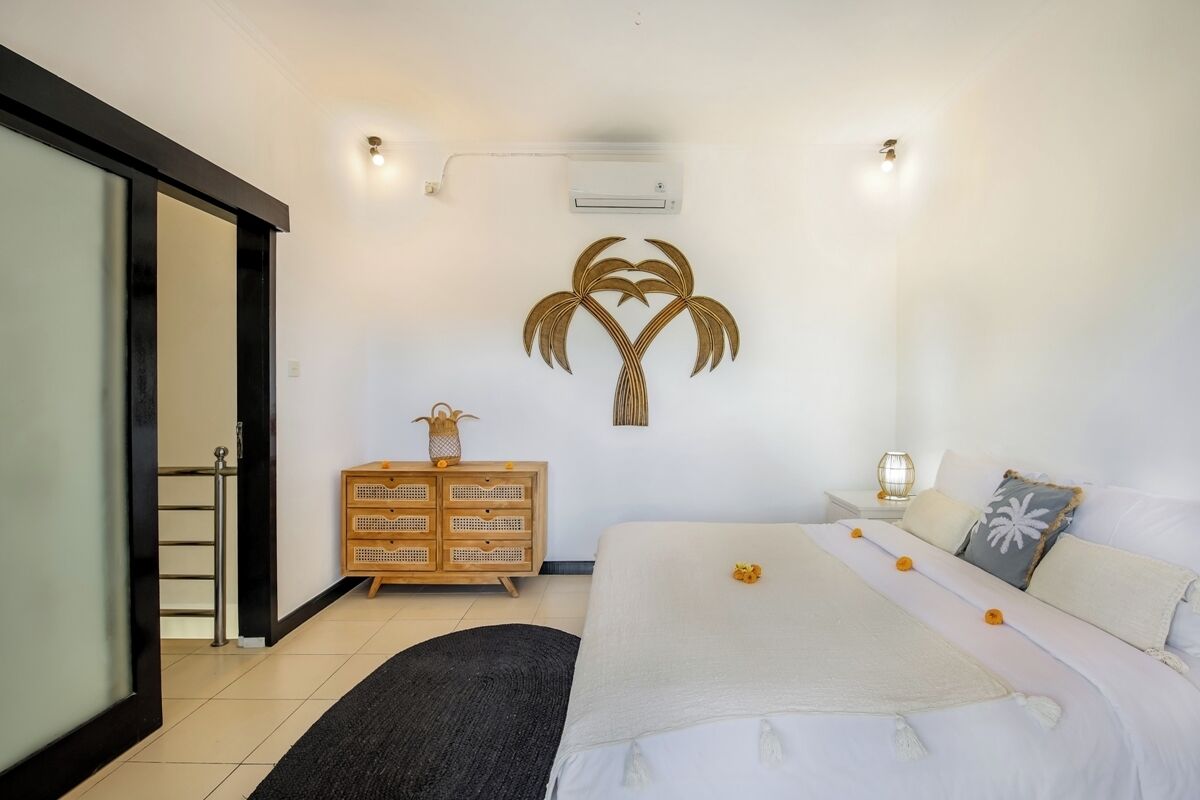 Une chambre à coucher comprenant un lit, une commode, un climatiseur fixé au mur et un élément décoratif mural.