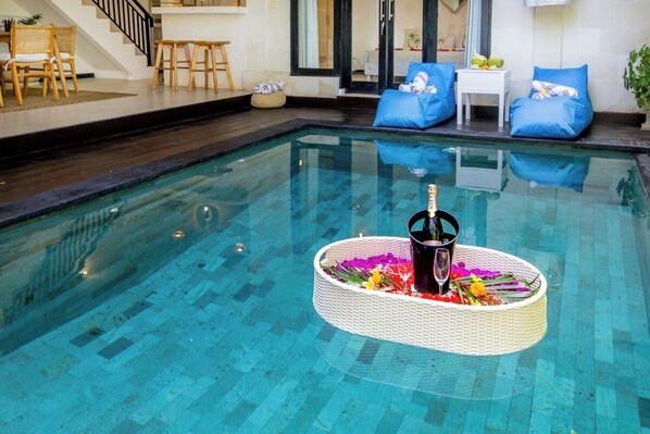 A swimming pool with a floating basket containing a bottle and flowers. - Cozy 3 BR Villa in Seminyak With Promo Rate (Seminyak)