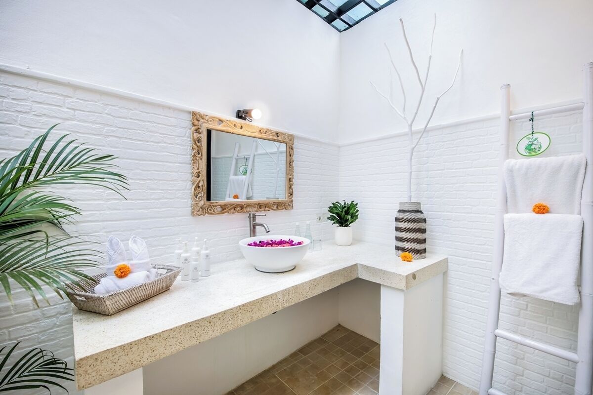 A bathroom with a white brick wall, a large mirror, a white sink, and a towel rack.