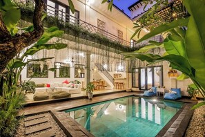 A poolside area with a clear pool, a staircase, and a seating area with cushions and a table. - Cozy 3 BR Villa in Seminyak With Promo Rate (Seminyak)
