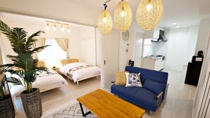 A modern living room with a sofa, a coffee table, and a bed with a large plant. - Ocean Terrace SESOKO 203 (Motobu)