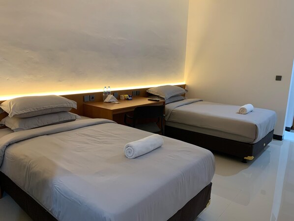 A hotel room with two beds, a desk, and a nightstand.