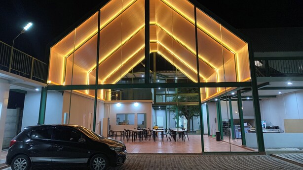 Een modern gebouw met een glazen gevel en een auto ervoor geparkeerd.
