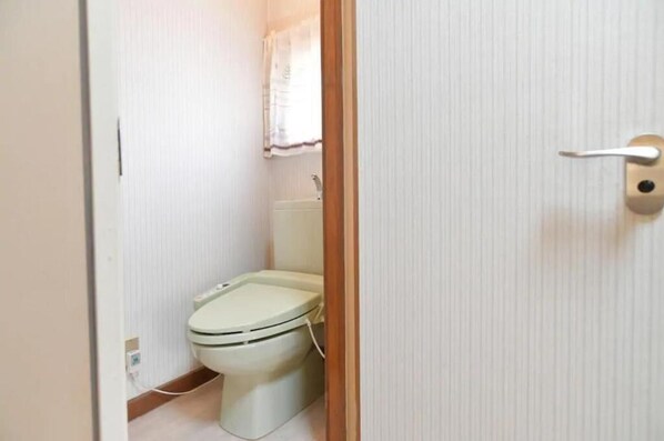 A small, compact bathroom with a toilet, a sink, and a window with a curtain. - STAY IN OTAKI (Date)