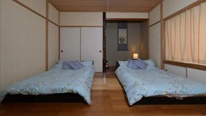 Une chambre avec deux lits, un plancher en bois et un luminaire au plafond.