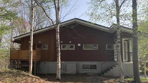 Une cabane dotée d’une terrasse en bois, d’un porche couvert et d’un petit escalier menant à l’entrée.