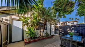 A patio area with a table and chairs, surrounded by plants and a small garden bed. - Coastal unit at sunset cliffs San Diego (San Diego)
