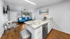 A modern kitchen with a marble countertop, white cabinetry, and a built-in dishwasher. - Coastal unit at sunset cliffs San Diego (San Diego)